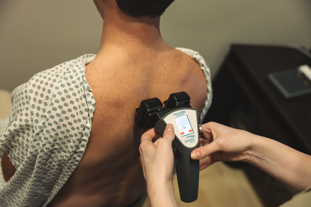 A surface EMG scan in progress at the upper back with the neuroCORE scanner