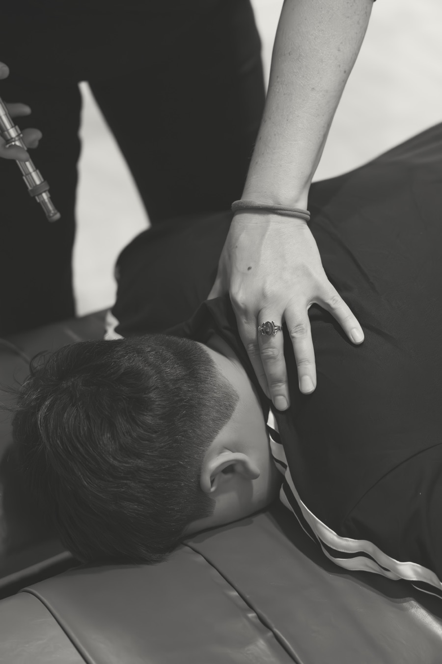 A hand checking a patient's upper back before an Integrator adjustment, in black and white