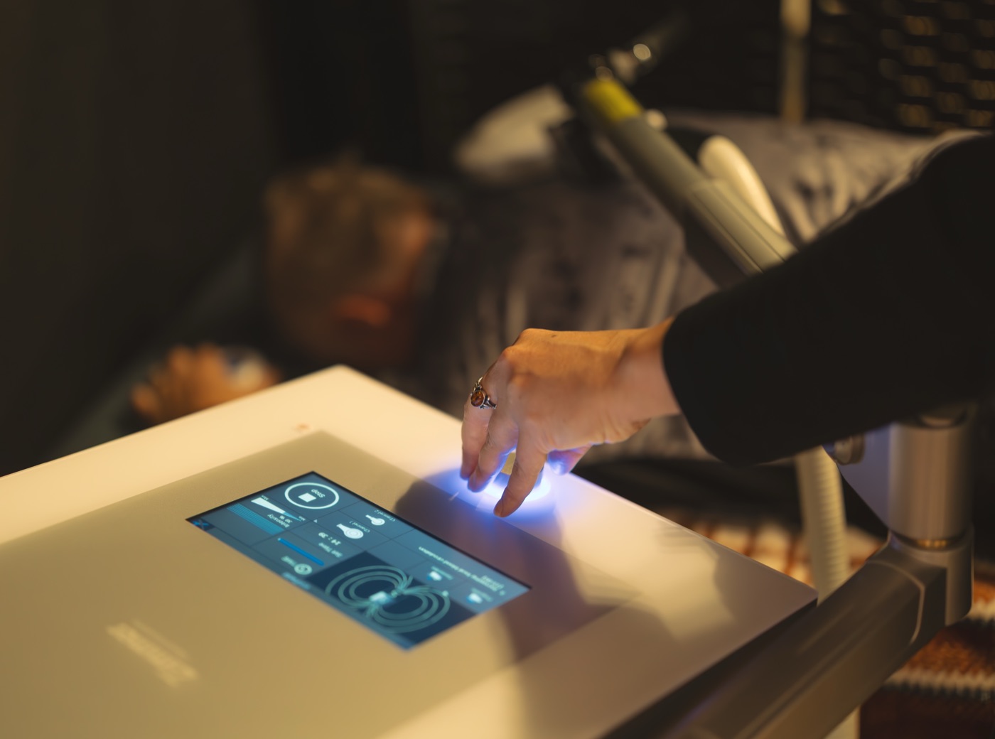 A hand on the emFieldPro's glowing control dial during a HEIT session