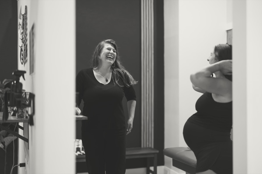 Dr. Sarah and a pregnant practice member laughing together, in black and white