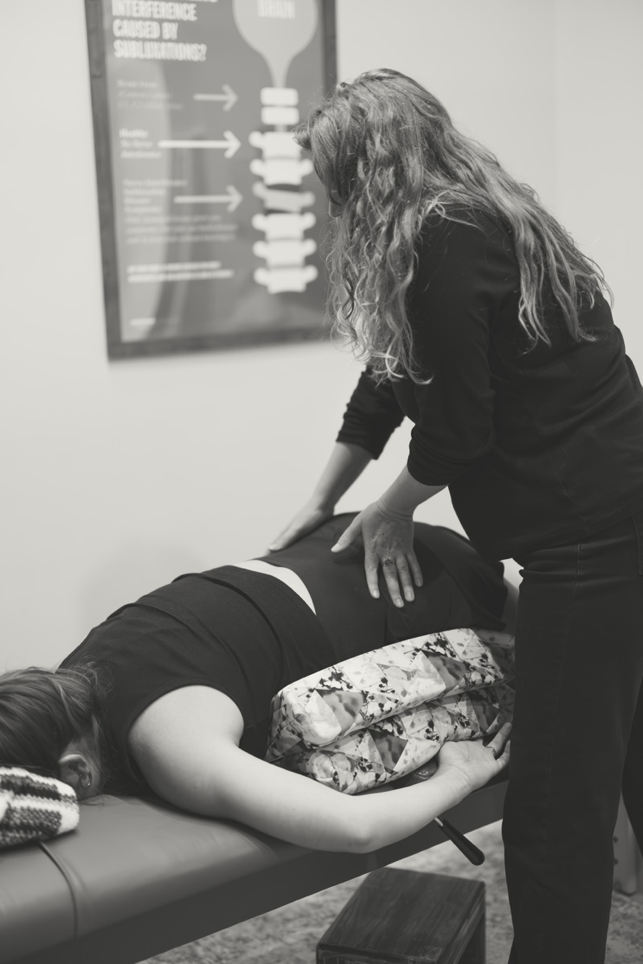 A prenatal adjustment with the pregnancy pillow, in black and white