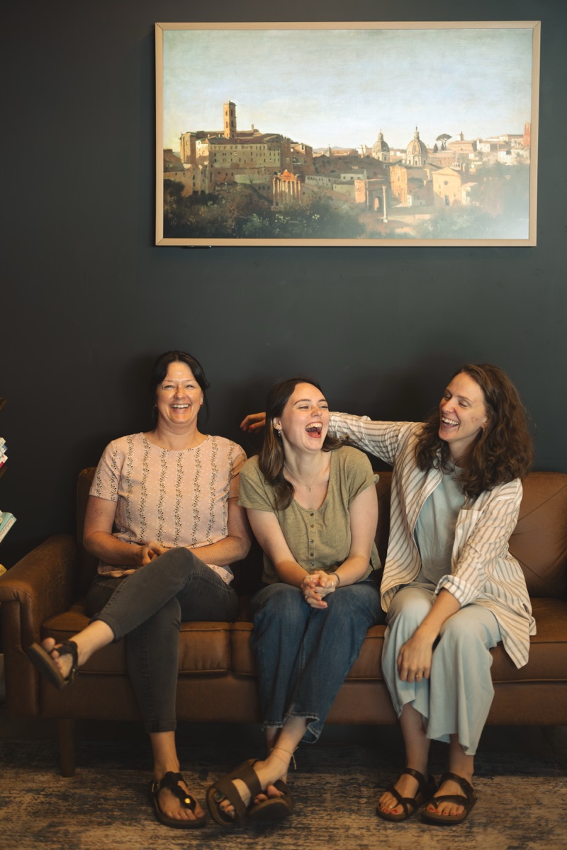 Mandy, Emily, and Gabriella laughing together on the lobby couch